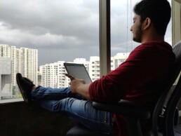 A young man sitting on his balcony, planning his financial goals on a tablet device.