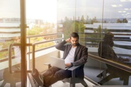 A man sitting on his balcony, using a laptop to review his real asset performance