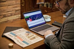 A man in business attire, sitting at his desk and reading financial news to gather insights about his risk tolerance.