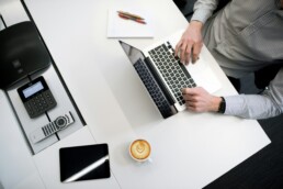 A top-down view of a man sitting at a desk, using a laptop to review his mutual funds and ETFs