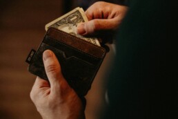 A man putting money into his wallet to save it for a rainy day amidst market volatility