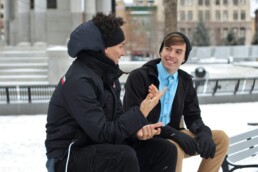 Two men sitting on a bench on a snowy day, discussing financial mistakes they'd like to avoid