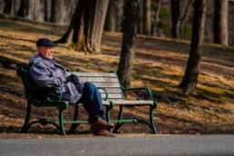 A retiree sitting on a park bench on a nice day, enjoying his social security benefits