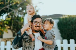 A man holding his two children out in the yard, secure because he took part in legacy planning