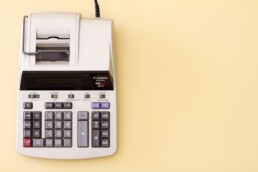 An adding machine used for financial check-ups, laying against a pale yellow background