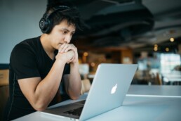 A young man sitting at a desk and using a laptop to manage his finances, exhibiting financial literacy